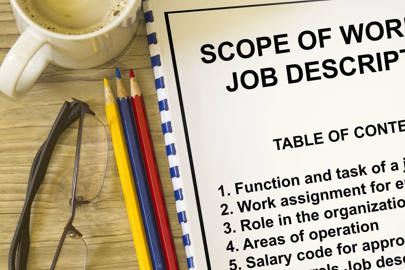 Pencils, glasses, coffee, and a notebook describing job descriptions